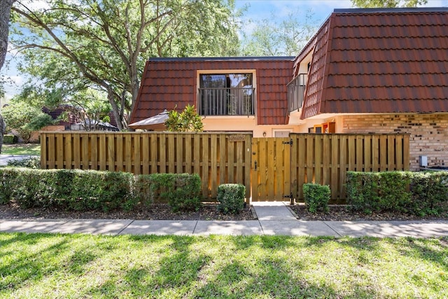 2626 2nd Ct, Palm Harbor, FL 34684 - view of side of home featuring mansard roof, brick siding, a gate, and a tile roof
