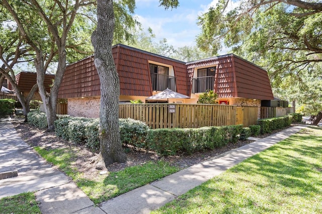 2626 2nd Ct, Palm Harbor, FL 34684 - view of side of property with brick siding, mansard roof, and fence