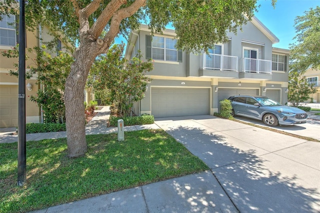 view of property featuring stucco siding, an attached garage, driveway, and a balcony