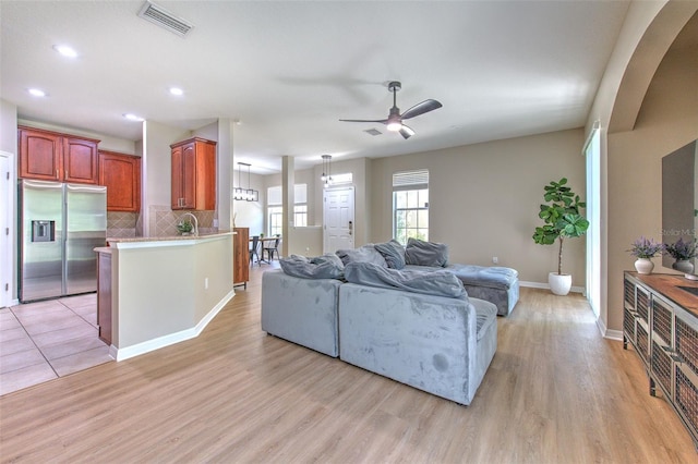 living area with a ceiling fan, light wood finished floors, baseboards, arched walkways, and recessed lighting