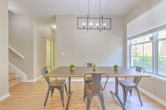dining space featuring a chandelier, plenty of natural light, baseboards, and light wood-type flooring