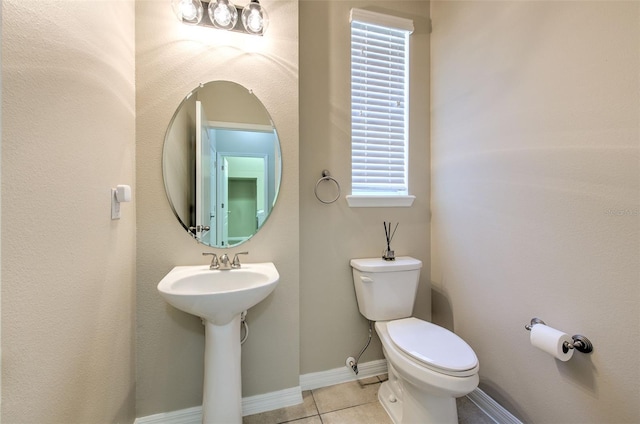 bathroom featuring toilet, tile patterned flooring, baseboards, and a sink