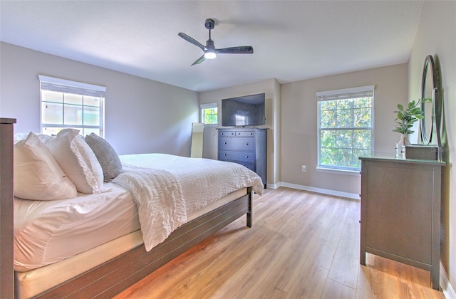 bedroom with light wood-type flooring, baseboards, and ceiling fan