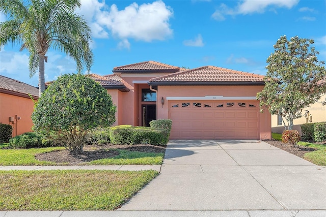 mediterranean / spanish-style home with an attached garage, stucco siding, a tile roof, and concrete driveway