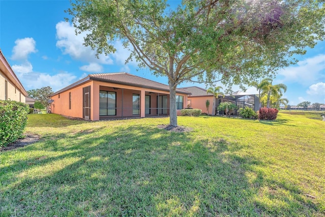 back of house featuring a yard, stucco siding, and a lanai