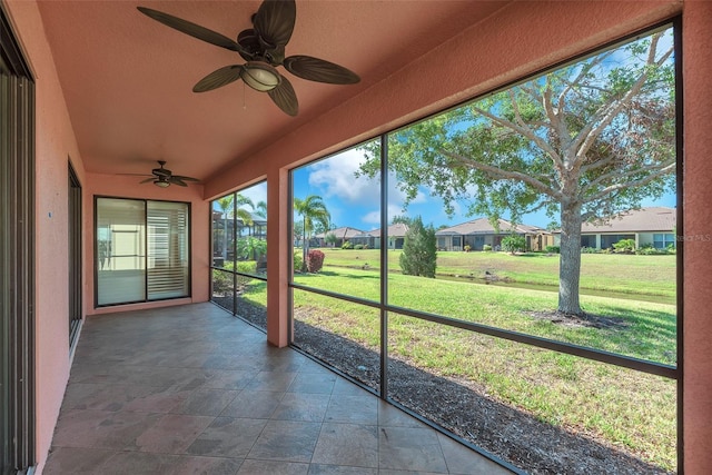 unfurnished sunroom featuring a ceiling fan, a residential view, and vaulted ceiling