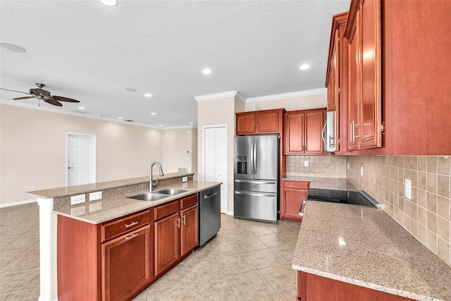 kitchen featuring stainless steel appliances, a sink, crown molding, a kitchen island with sink, and backsplash