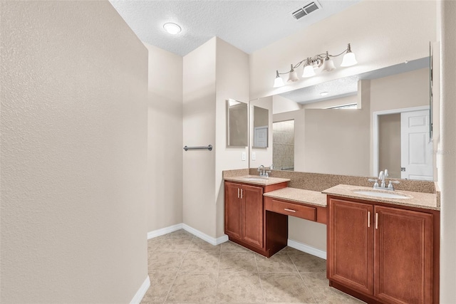 full bathroom with double vanity, baseboards, tile patterned floors, and a textured ceiling