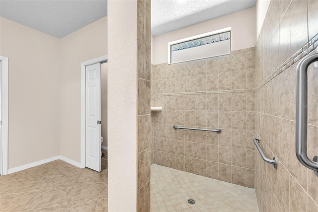 bathroom with a stall shower, toilet, tile patterned flooring, and a textured ceiling