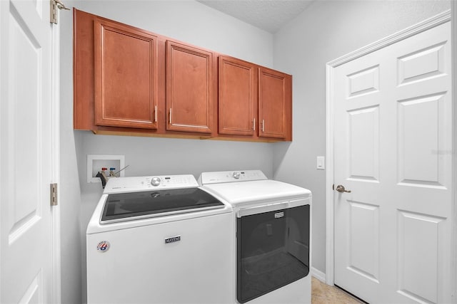 clothes washing area featuring washing machine and clothes dryer, cabinet space, light tile patterned flooring, and a textured ceiling