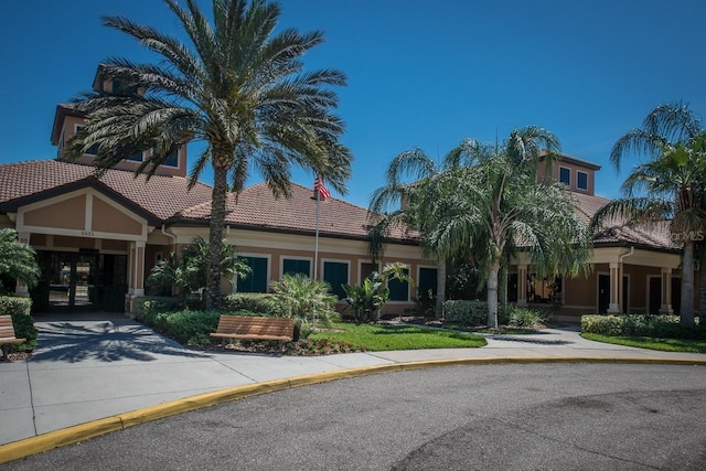 view of front of property with a tile roof, stucco siding, and driveway