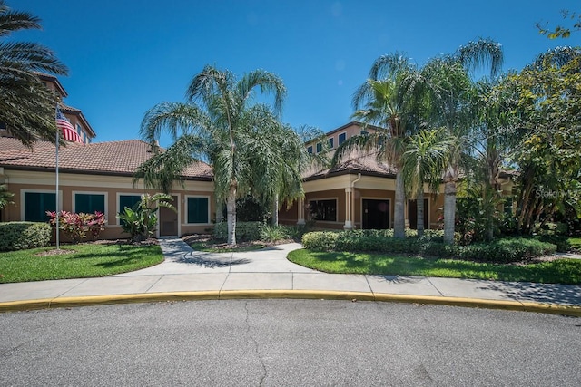view of front of house with a tile roof, stucco siding, a front yard, and a balcony