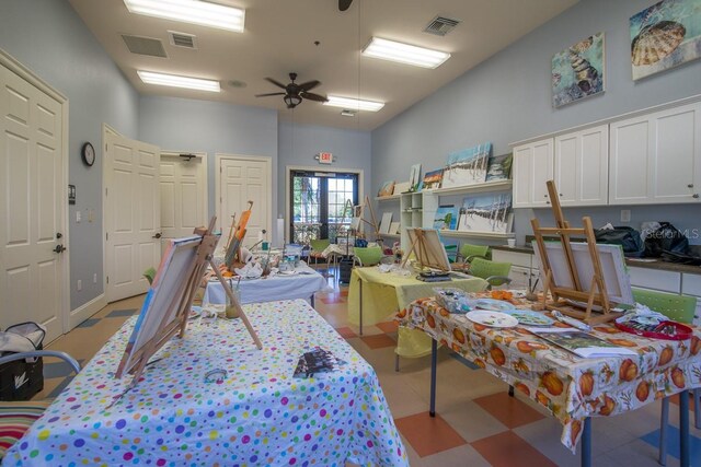miscellaneous room with ceiling fan, light flooring, and a towering ceiling