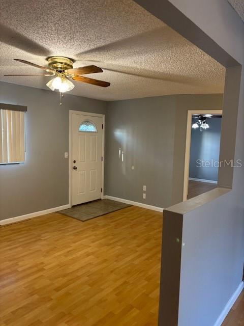12230 Skyler Ln, Spring Hill, FL 34609 - entrance foyer with ceiling fan, baseboards, light wood finished floors, and a textured ceiling