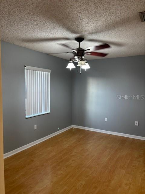 12230 Skyler Ln, Spring Hill, FL 34609 - unfurnished room featuring wood finished floors, ceiling fan, a textured ceiling, and baseboards