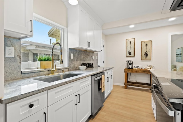 5724 Dr Martin Luther King Jr St N Unit J, Saint Petersburg, FL 33703 - kitchen featuring appliances with stainless steel finishes, a sink, backsplash, light wood-style flooring, and white cabinetry