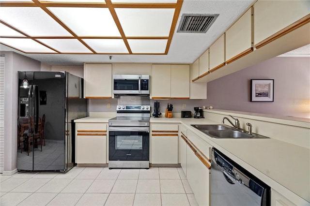 18400 Gulf Blvd Unit 1105, Indian Shores, FL 33785 - kitchen with stainless steel appliances, cream cabinets, a sink, light countertops, and light tile patterned flooring