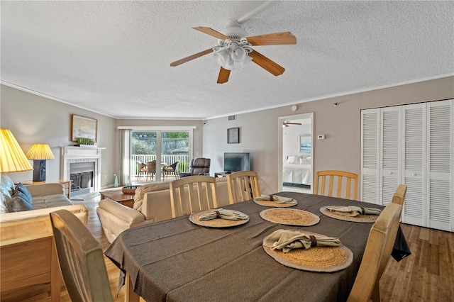 18400 Gulf Blvd Unit 1105, Indian Shores, FL 33785 - dining area with a textured ceiling, a ceiling fan, wood finished floors, ornamental molding, and a tiled fireplace