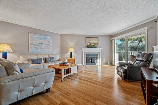 18400 Gulf Blvd Unit 1105, Indian Shores, FL 33785 - living room with crown molding, a textured ceiling, light wood-style flooring, and a fireplace