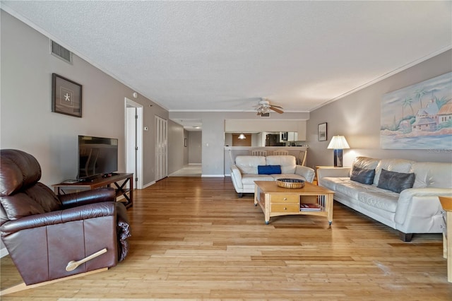 18400 Gulf Blvd Unit 1105, Indian Shores, FL 33785 - living room with crown molding, light wood finished floors, a textured ceiling, and a ceiling fan