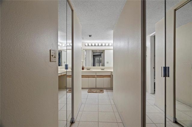 18400 Gulf Blvd Unit 1105, Indian Shores, FL 33785 - hallway with a textured wall, a textured ceiling, light tile patterned floors, and a sink