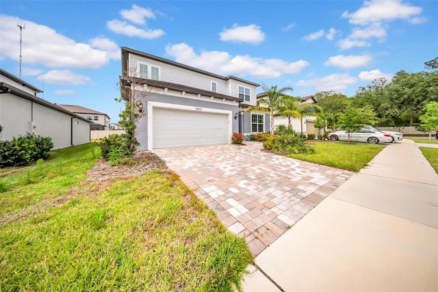 traditional home featuring decorative driveway, a front lawn, a garage, and stucco siding