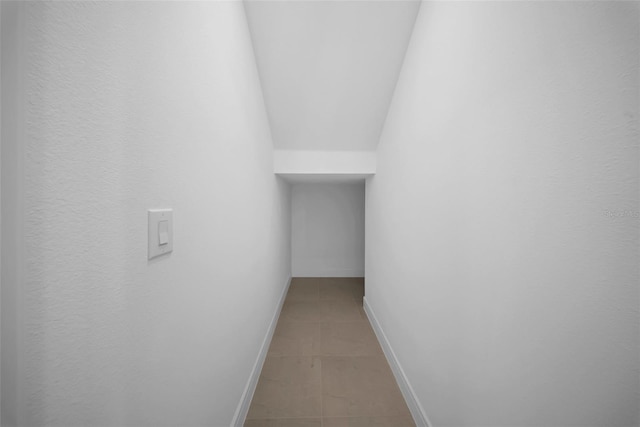 corridor with light tile patterned floors and baseboards