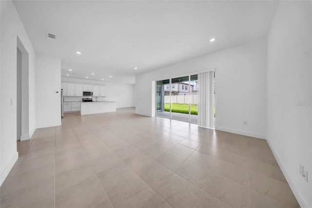 unfurnished living room with recessed lighting, light tile patterned floors, and baseboards