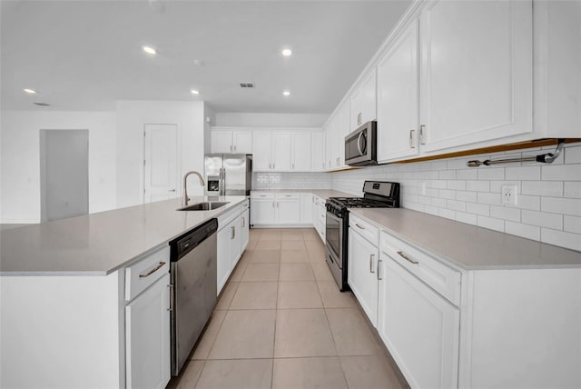 kitchen featuring appliances with stainless steel finishes, a sink, decorative backsplash, white cabinetry, and light tile patterned flooring