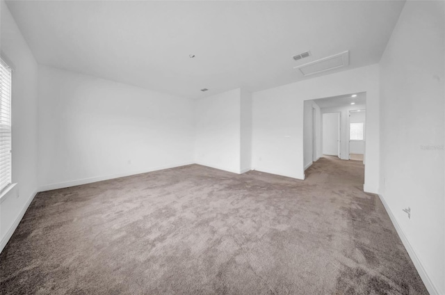 carpeted spare room with attic access and baseboards