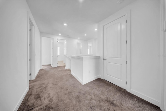 hall with carpet floors, baseboards, and recessed lighting