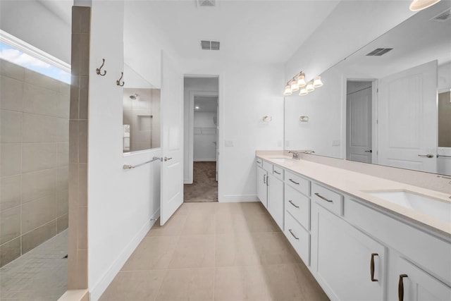 bathroom featuring a walk in shower, double vanity, tile patterned flooring, and baseboards