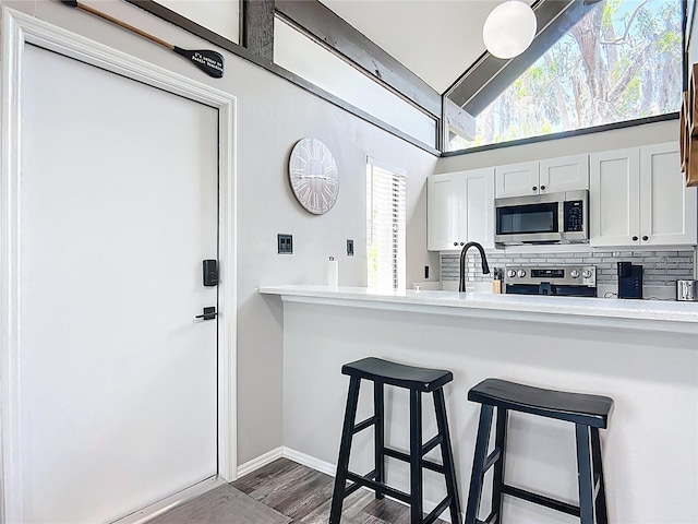 2653 N Seabreeze Pt Unit M-2, Crystal River, FL 34429 - kitchen with appliances with stainless steel finishes, backsplash, a breakfast bar area, light countertops, and dark wood-type flooring
