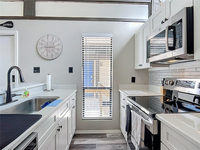 2653 N Seabreeze Pt Unit M-2, Crystal River, FL 34429 - kitchen featuring appliances with stainless steel finishes, a sink, light wood-type flooring, backsplash, and white cabinets