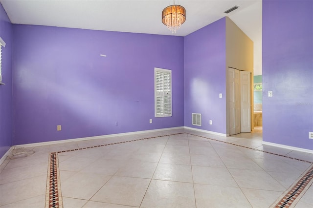 3013 Crest Dr, Clearwater, FL 33759 - empty room featuring tile patterned flooring, baseboards, a chandelier, inlaid floor details, and lofted ceiling