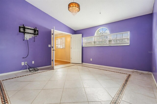 3013 Crest Dr, Clearwater, FL 33759 - empty room with tile patterned floors, lofted ceiling, baseboards, and inlaid floor details