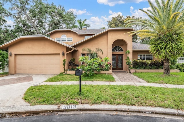 3013 Crest Dr, Clearwater, FL 33759 - view of front of house featuring french doors, stucco siding, a garage, driveway, and a front yard