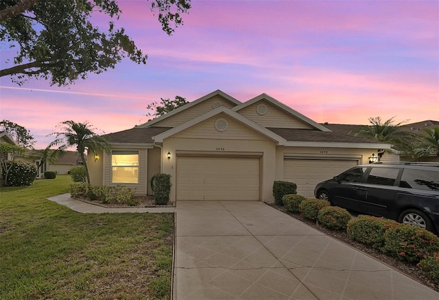 ranch-style house featuring a yard, a garage, driveway, and stucco siding