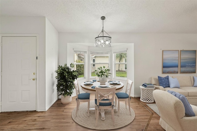 dining area with a chandelier, a textured ceiling, wood finished floors, and baseboards