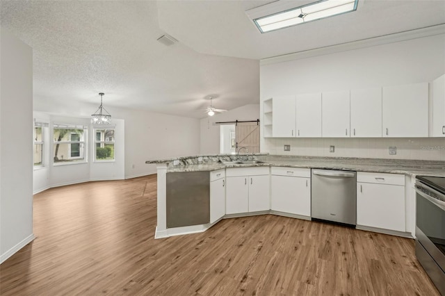 kitchen with stainless steel appliances, a peninsula, a sink, light wood-style floors, and white cabinetry