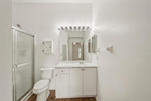 full bath with a stall shower, wood finished floors, toilet, and vanity