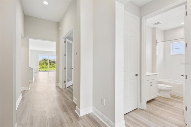 hallway with light wood-style flooring, plenty of natural light, baseboards, and recessed lighting