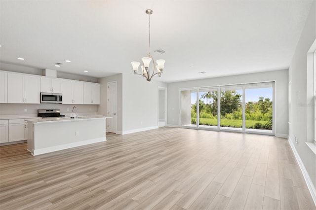 kitchen with stainless steel appliances, light countertops, open floor plan, a chandelier, and baseboards