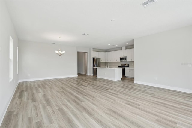 unfurnished living room featuring a chandelier, baseboards, light wood-type flooring, a sink, and recessed lighting