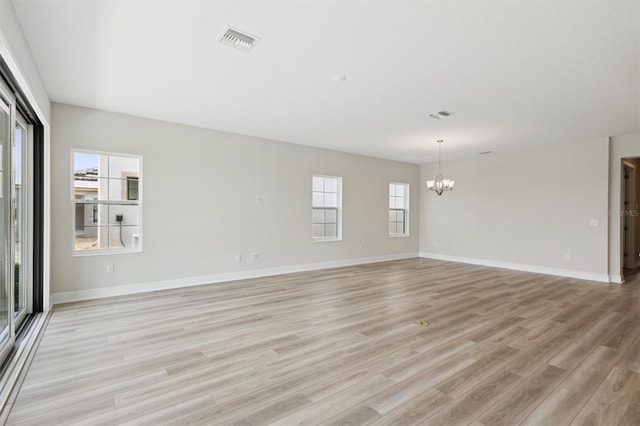 unfurnished room featuring a chandelier, light wood-style flooring, and baseboards