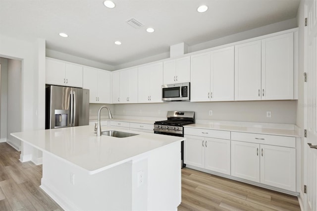 kitchen with stainless steel appliances, a sink, light wood-type flooring, white cabinets, and recessed lighting