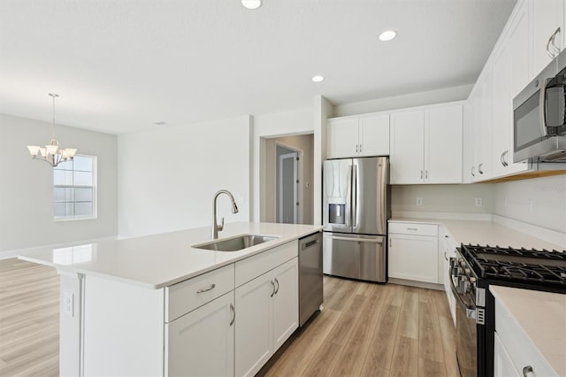 kitchen with appliances with stainless steel finishes, a sink, light wood finished floors, light countertops, and recessed lighting