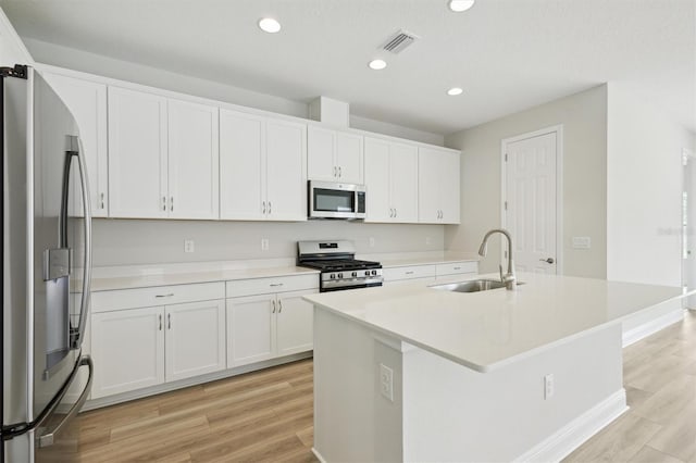 kitchen featuring stainless steel appliances, a sink, light wood-type flooring, white cabinetry, and recessed lighting