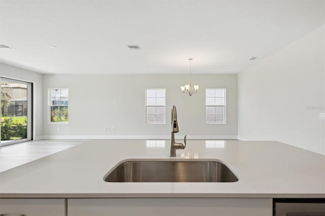 kitchen with open floor plan, a sink, decorative light fixtures, a chandelier, and an island with sink