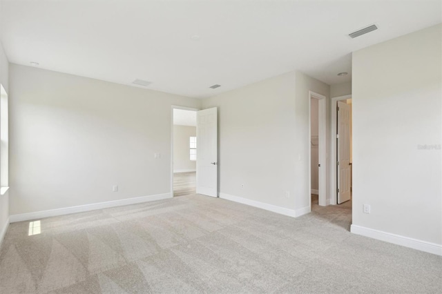 unfurnished room featuring light carpet and baseboards